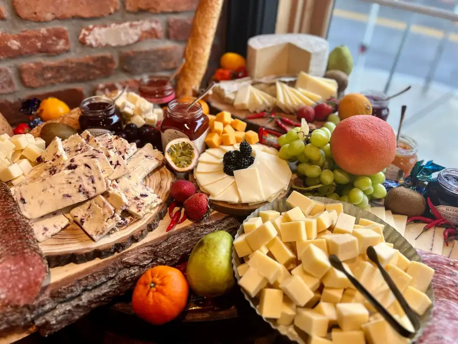 A catered grazing board of cheeses, fruit and cured meats on brick