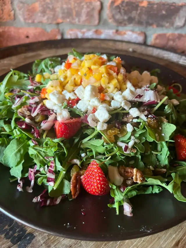 Salad topped with diced mango and strawberries