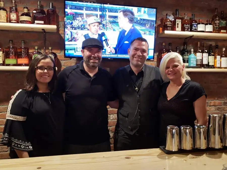 The Charred Oak Tavern team smiling behind the bar