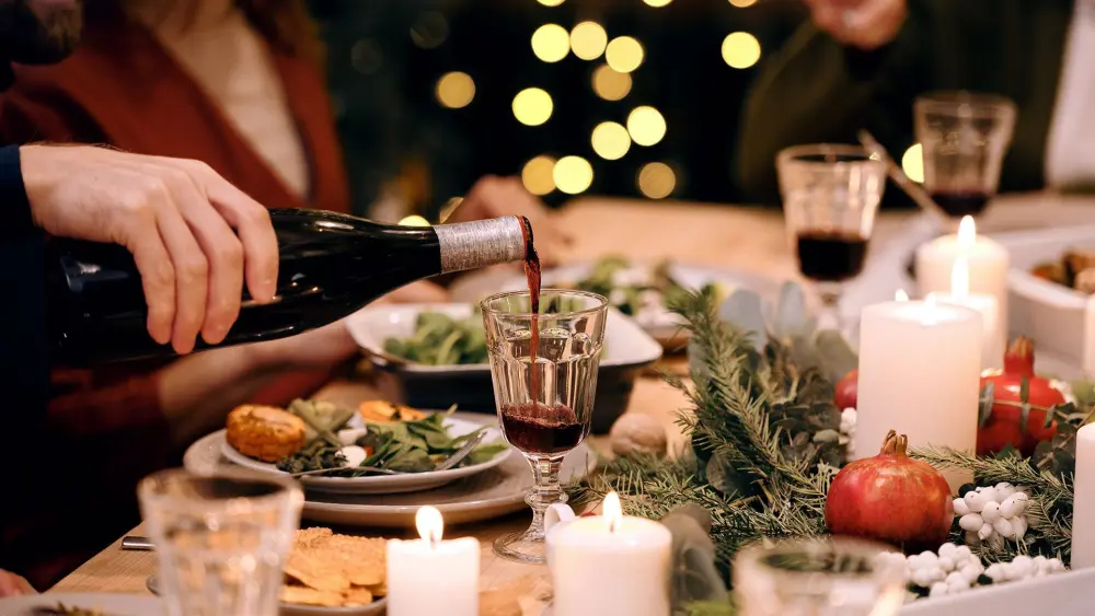 Red wine poured at a candlelit holiday table